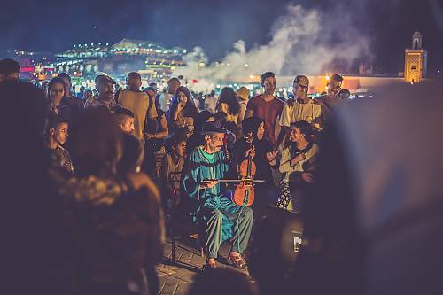 Joueur de violon sur la place Jemaa el-Fna avec une foule de gens et le marché