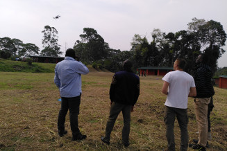 5 men standing and flying a drone in Uganda