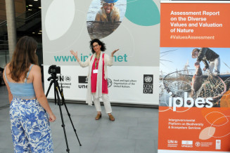 Meriem Bouamrane, UNESCO, posing in front IPBES banner during IPBES9