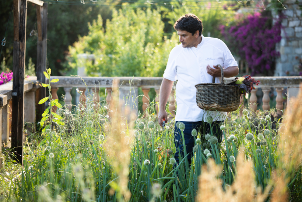 Mauro Colagreco en el jardín del Mirazur, su restaurante de Menton. Lleva una cesta llena de hierbas frescas en el brazo izquierdo y cizallas en la mano derecha mientras selecciona las plantas que cocinará ese día.