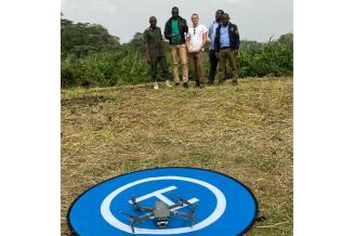 4 men standing in background piloting a drone. Drone on foreground on take off/landing piste