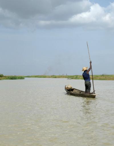 man standing on pirogue fishing in lake chad