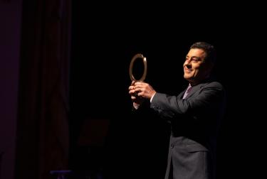 Picture of Zafer Kizilkaya holding a trophy, standing on stage at the Goldman Environmental Prize