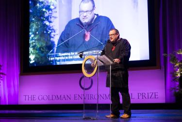 Picture of Tero Mustonen on stage during the Goldman Environmental Prize ceremony reading a speech 