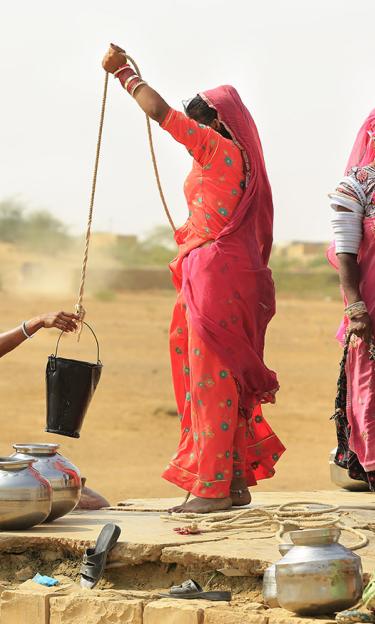 Women draw water from the well in a rural area of of Jaisalmer, India