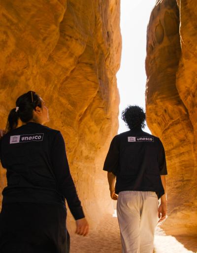 Two UNESCO personnel walking amidst the natural landscape of AlUla