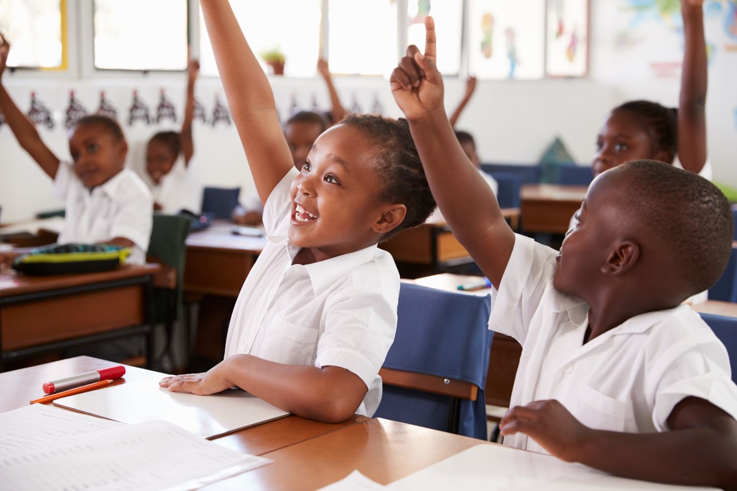 Des enfants qui lèvent la main lors d'une leçon à l'école primaire.