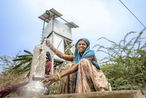 A woman fills a pot with drinking water at a public fountain in India